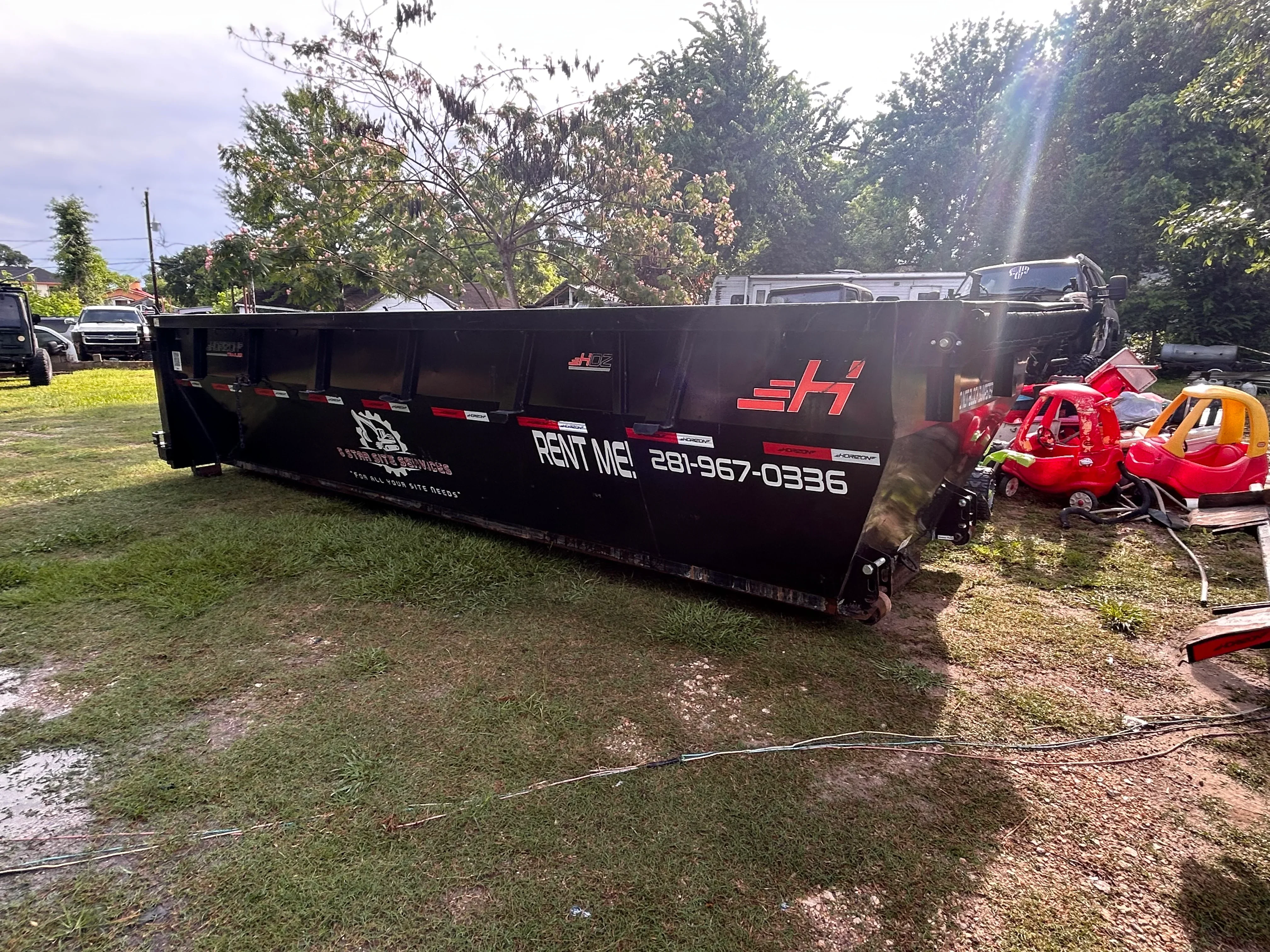 Black steel roll-off dumpster with red reflective striping for waste hauling and debris removal