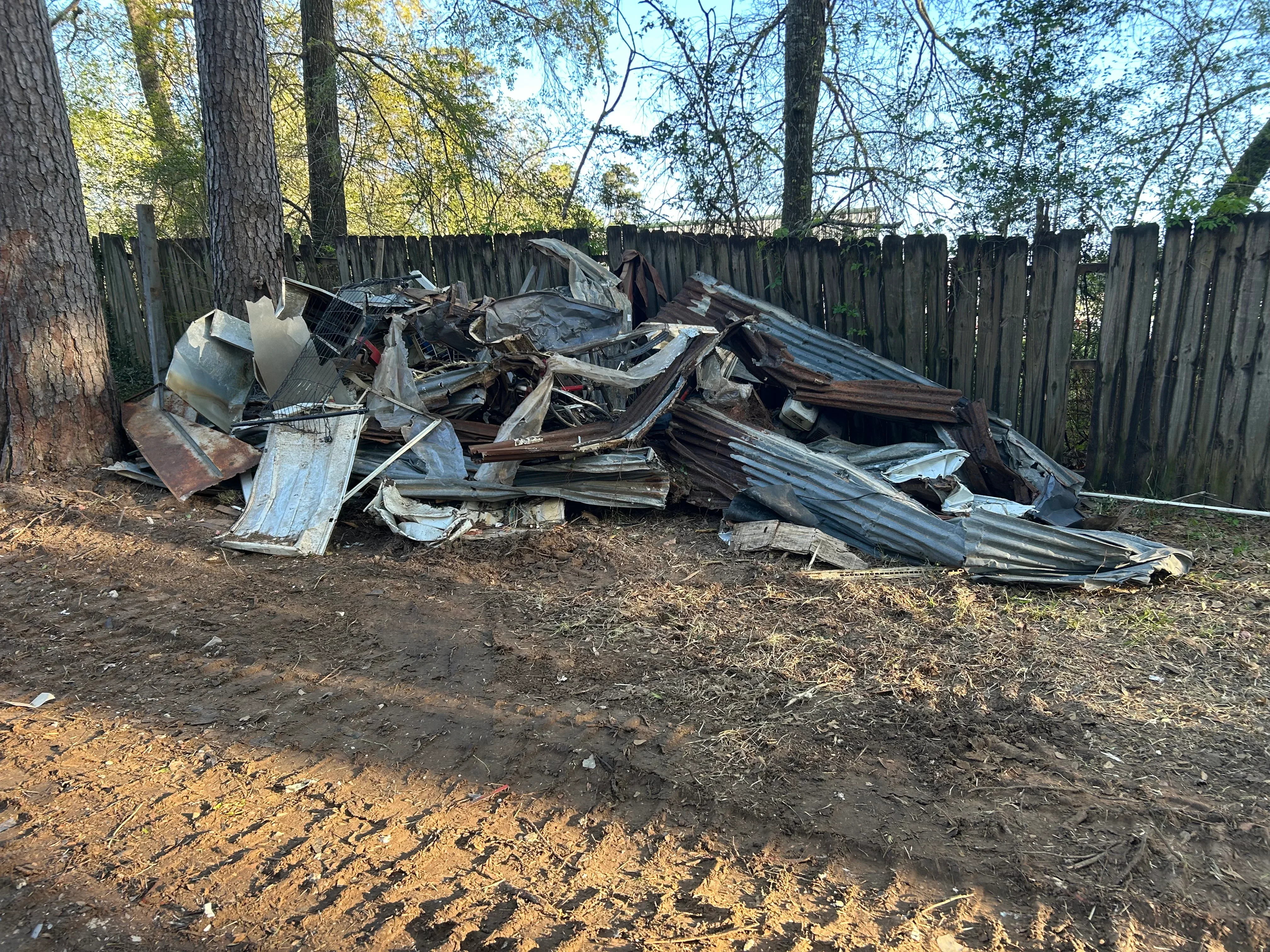 Pile of mixed metal roofing, wood framing, and construction debris staged for removal