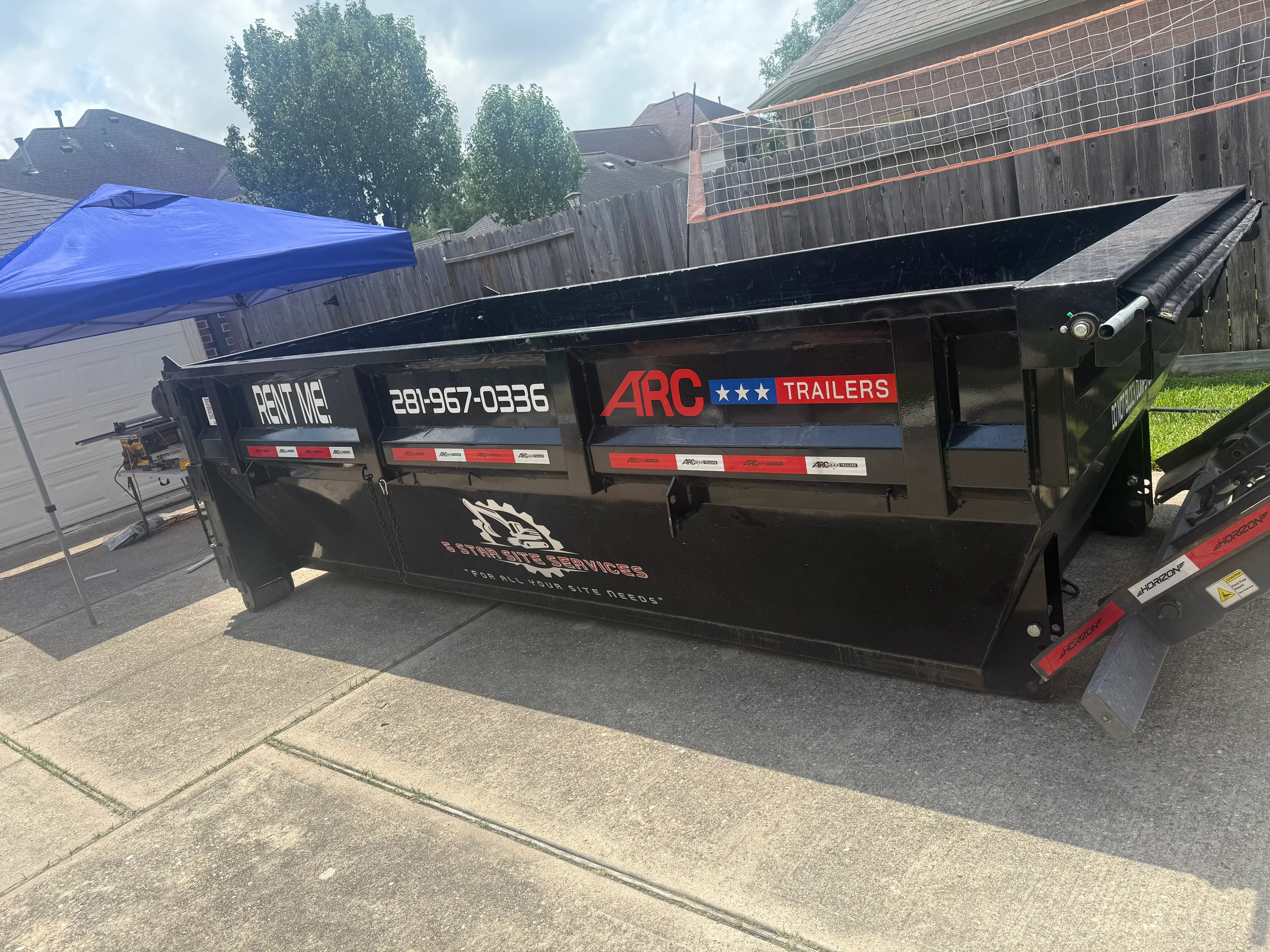 Black flatbed trailer with custom vinyl wrap, red and white branding, and contact information