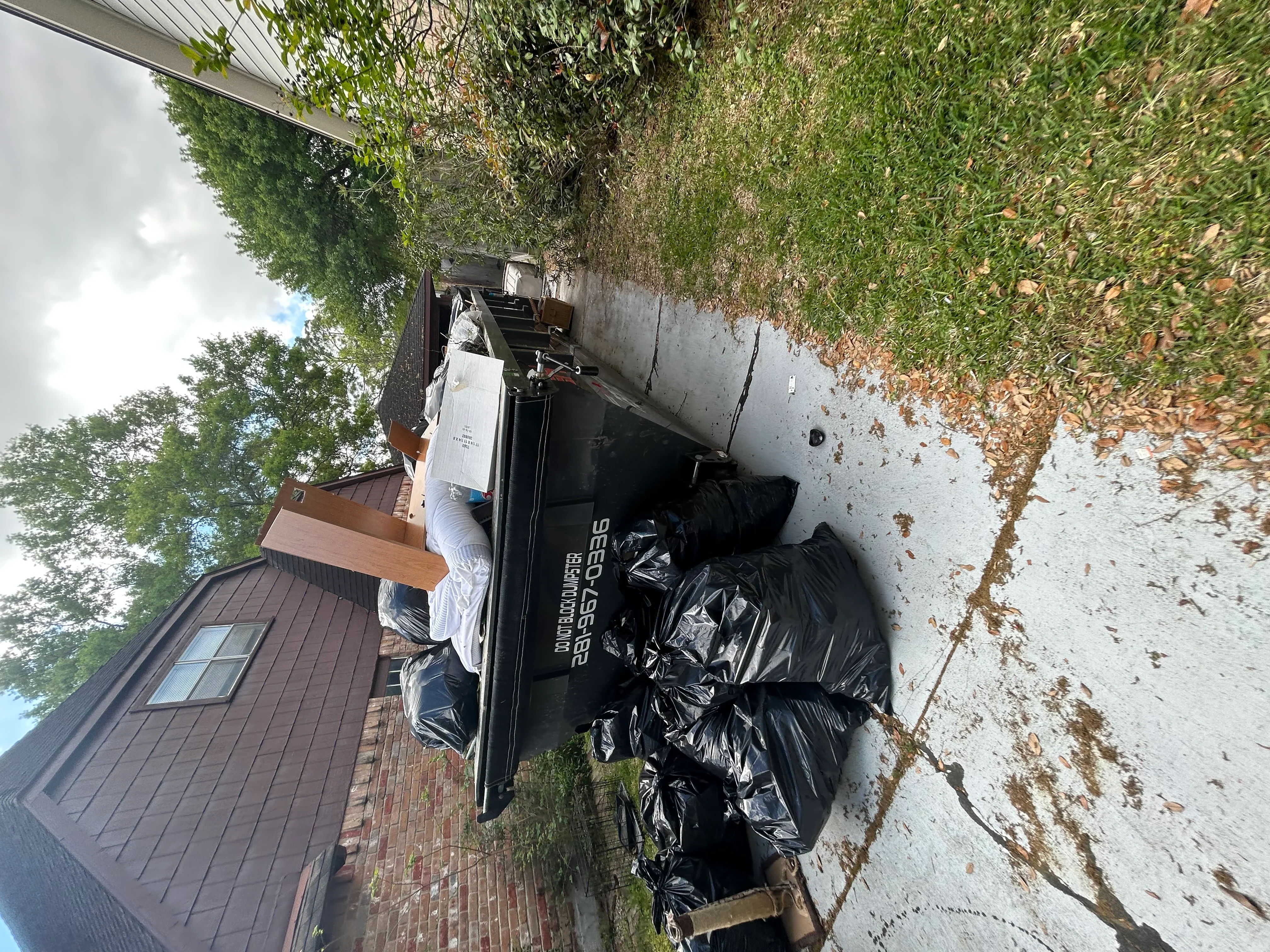 Dumpster truck loaded with black garbage bags and debris removal from residential property