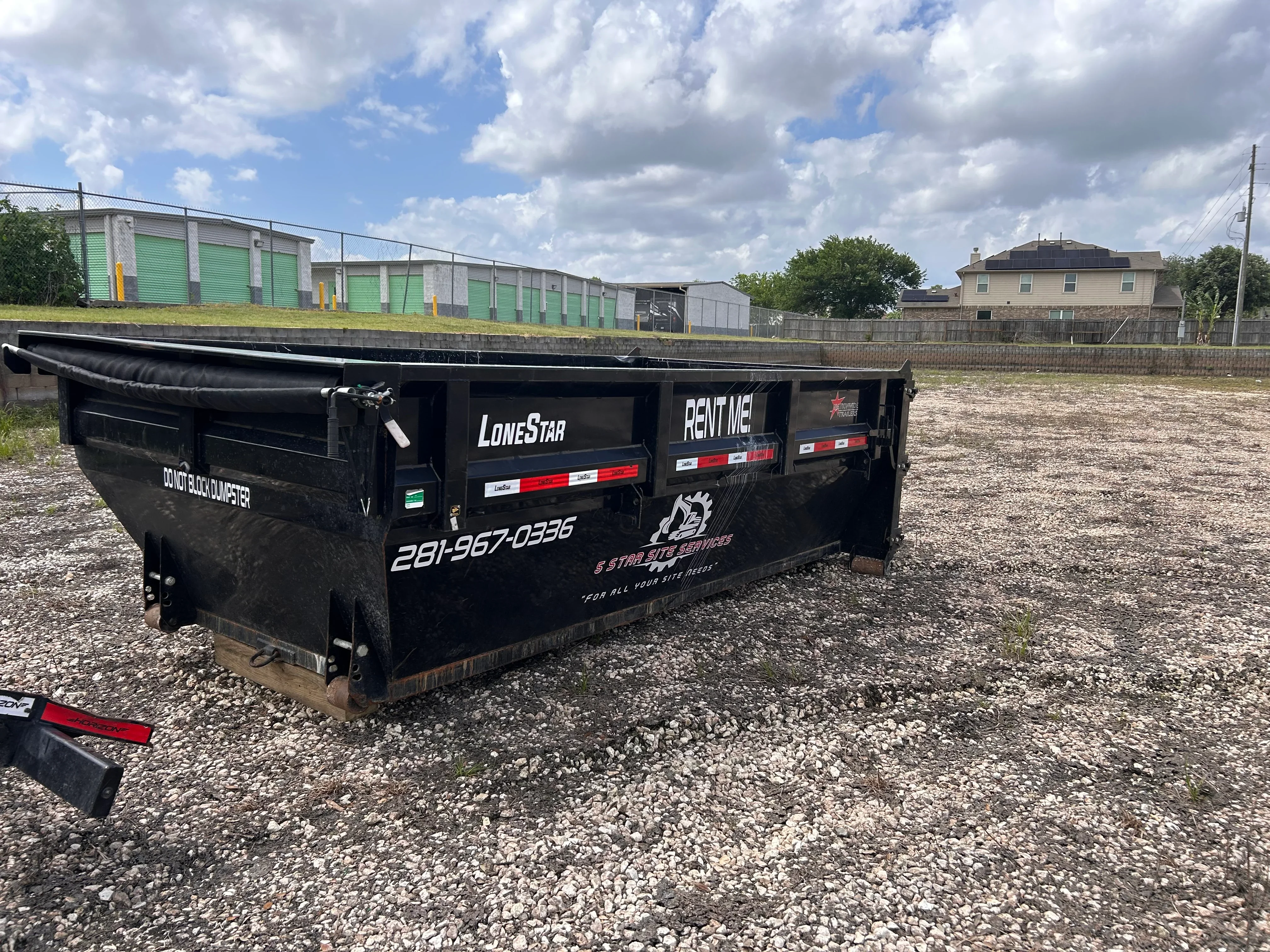 Black steel roll-off dumpster trailer with red safety lights and reflective striping for commercial hauling